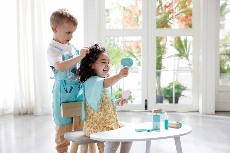 Niños jugando con el juego de peluquería superelegante de Hape
